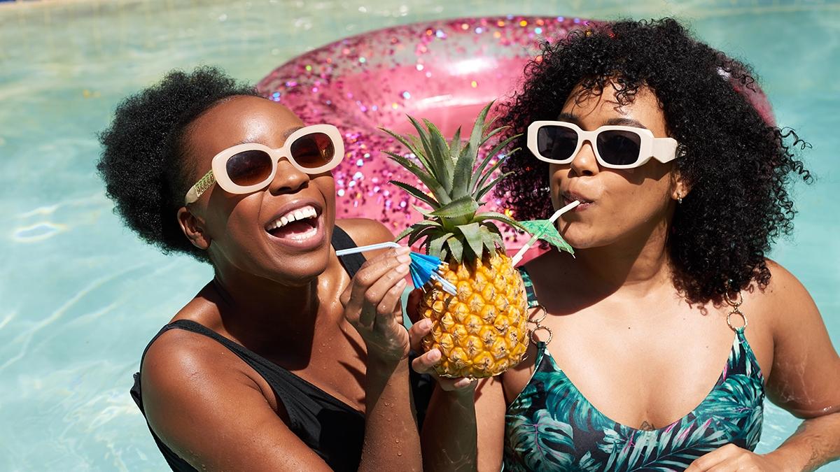 Article Cards Featured Image Two Black friends drink pineapple drink in the swimming pool on summer vacation