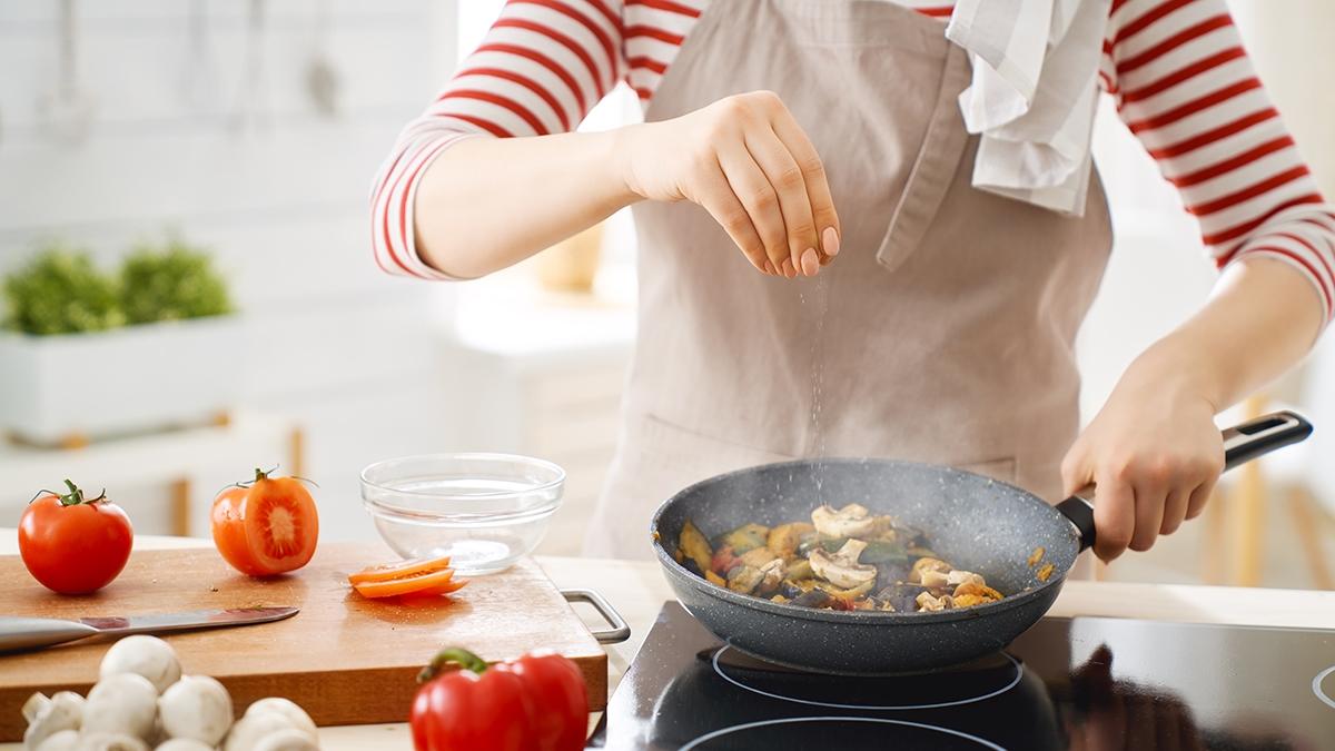 Article Cards Featured Image Healthy food at home. Happy woman is preparing the proper meal in the kitchen.