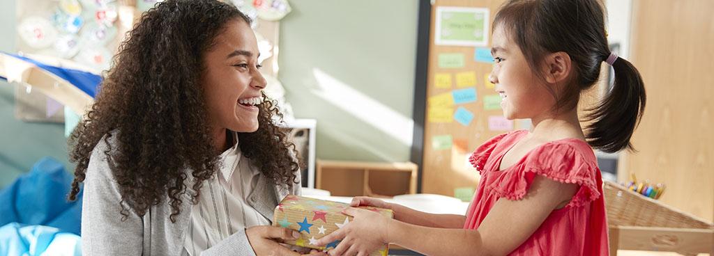 A young girl giving a woman a gift.