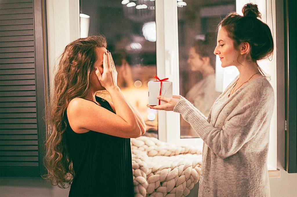 A woman giving a gift to another woman.