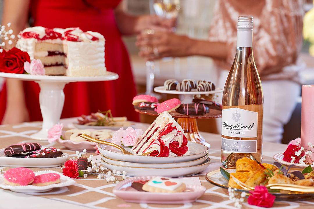 Galentine's day desserts on plates next to a bottle of wine.