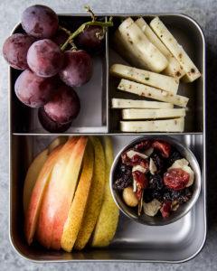 Road trip snack with fruit, cheese, and trail mix.