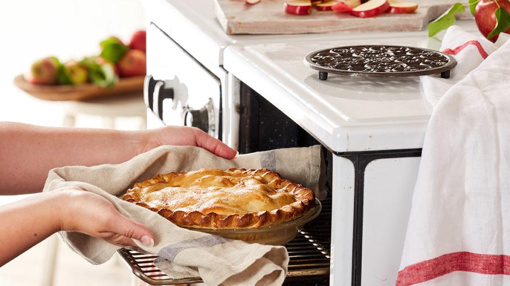 A photo of Thanksgiving dinner and someone putting a pie in the oven