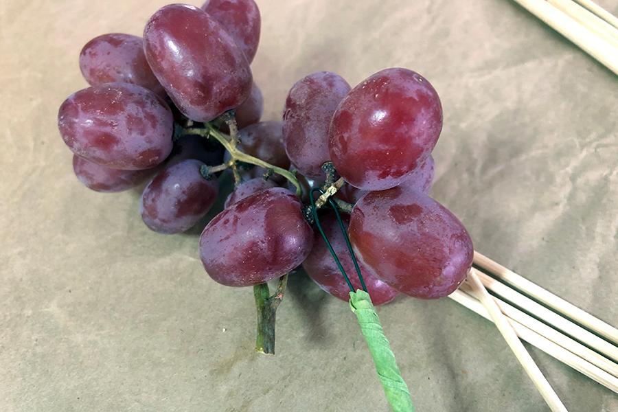 A photo of a pear tablescape with grapes on a wire