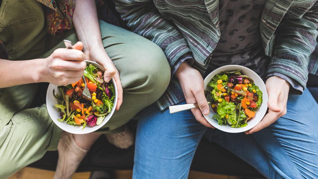 Comfort food with two people eating bowls of salad.