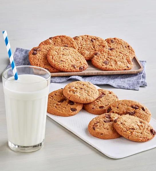 Gluten free cakes with plates of cookies next to a glass of milk.