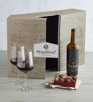 Box of truffles next to a bottle of reserve wine and two glasses.