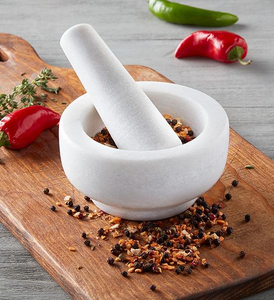 Gifts for the home cook with a white mortar and pestle full of spices.