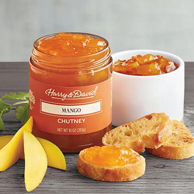 Jar of mango chutney next to slices of mango.